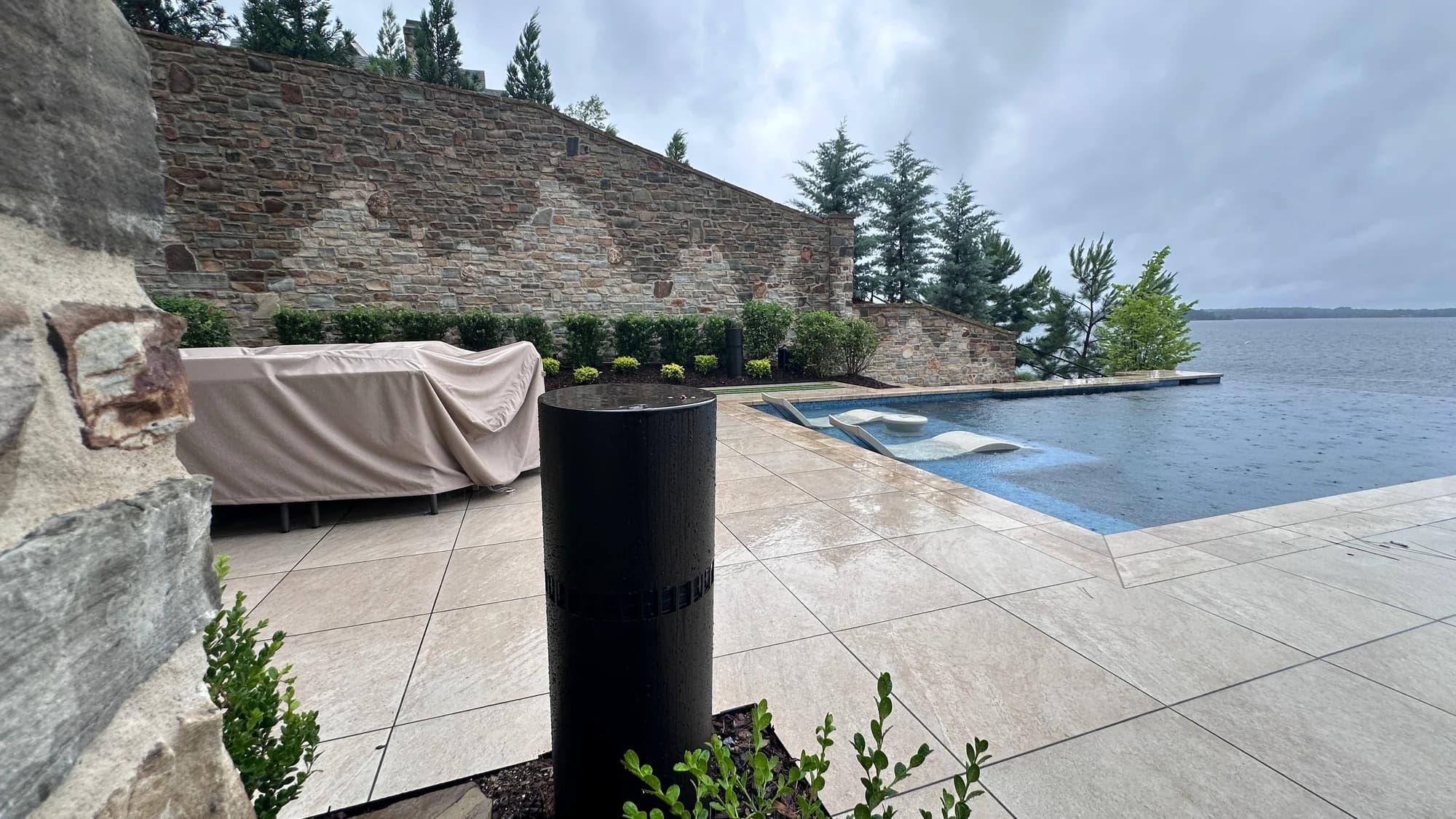 Outdoor audio installation beside a pool and landscaped stone terrace
