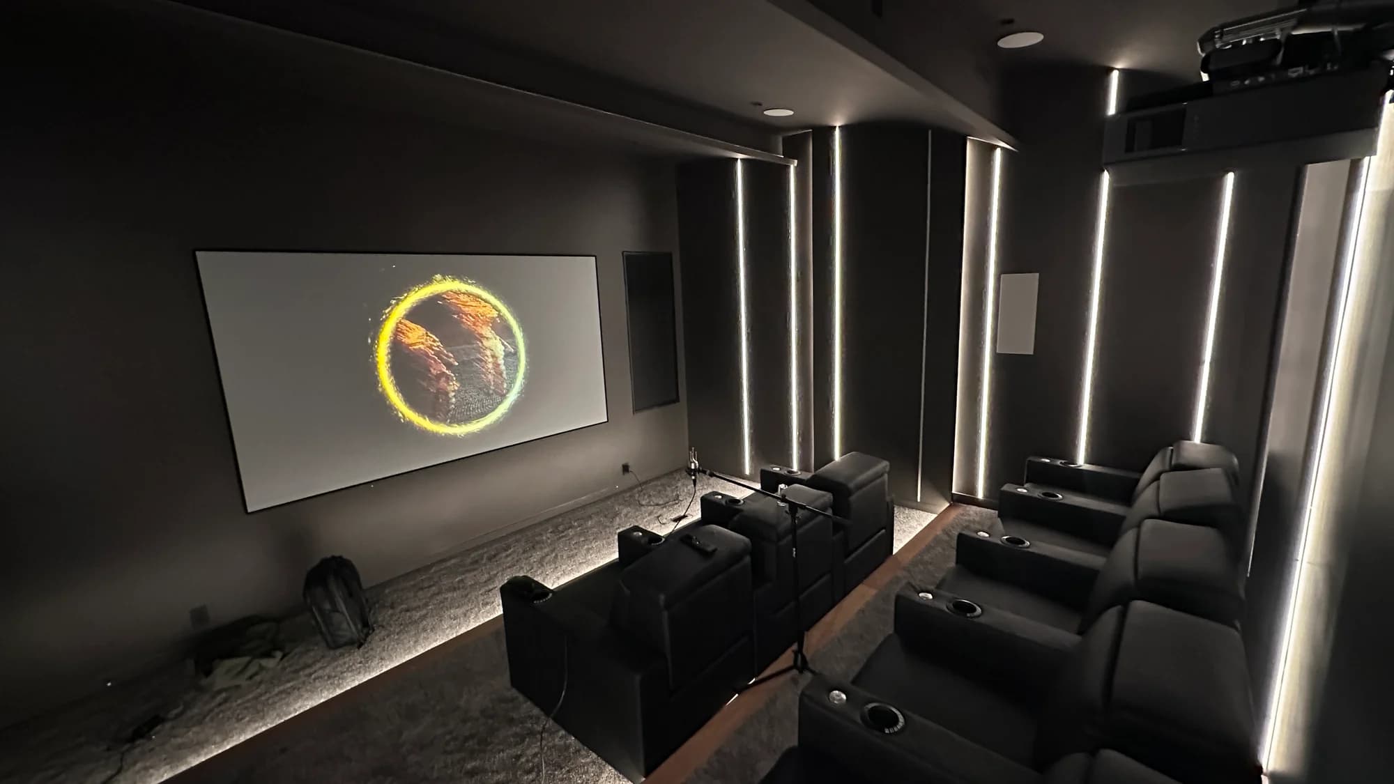 Dedicated theater with projection screen, two rows of recliners, and vertical wall lighting